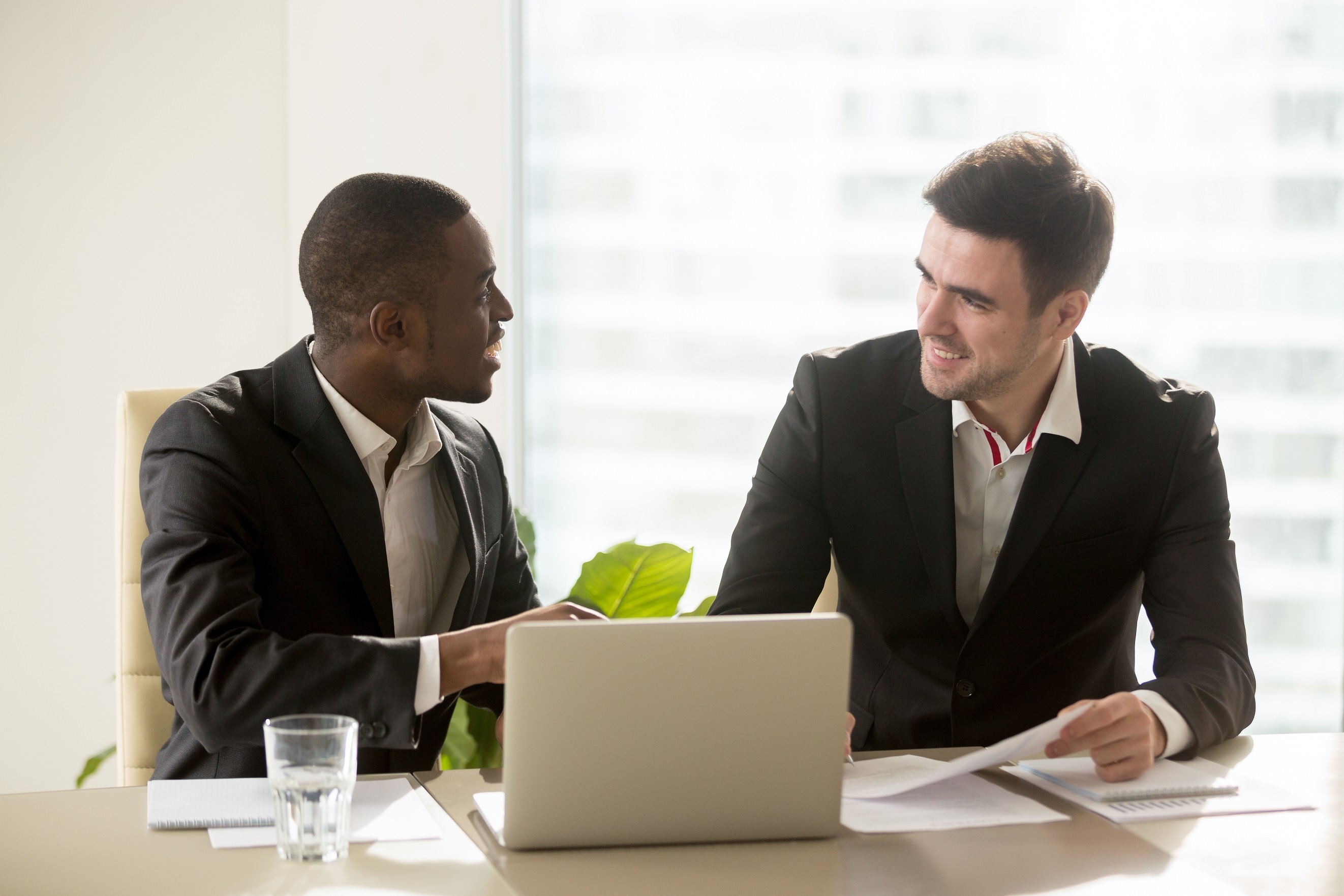 two accomplished multiracial businessmen discussing idea new business projects at office desk, multi ethnic business group having pleasant time